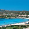 Spiaggia con mare azzurro e paesaggio collinare.