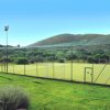 Campo sportivo all'aperto con rete e colline sullo sfondo.