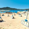 Spiaggia con lettini chiusi e ombrelloni, mare in lontananza.