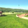 Campo sportivo recintato con erba verde e sentiero curvo.
