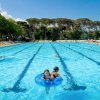Grande piscina all'aperto con persone che nuotano.