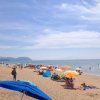 Spiaggia affollata di ombrelloni colorati e persone.