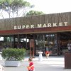 Entrata di un supermercato con persone sedute.