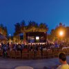 Persone sedute attorno a un palco all'aperto di sera.
