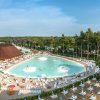 Grande piscina con lettini e capanne di paglia.