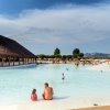 Piscina con fontana, persone e capanna di legno.