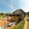 Piscina con lettini, ombrelloni colorati e un edificio giallo con tetto di paglia.