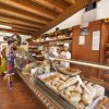 Interno di un panificio con espositori di pane e prodotti da forno, cliente e commesso al banco.