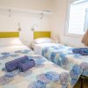 Una camera da letto con due letti singoli coperti da coperte blu e bianche, finestra e mensola.