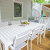 Tavolo bianco con sei sedie su un patio di legno.