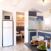 Cucina e zona pranzo con tavolo, frigo, e stoviglie, vicino a due stanze da letto.