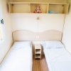 Due letti singoli con lenzuola bianche, mensola con peluche e libro.