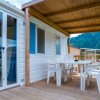 Terrazza con tavolo e sedie bianche, coperta da tettoia in legno.
