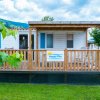 Una casa mobile bianca con veranda in legno su un prato.
