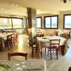 Ristorante con tavoli apparecchiati, grandi finestre e vista sul mare.