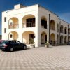 Edificio a due piani con archi, auto parcheggiata davanti.