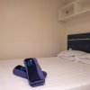 Letto matrimoniale con lenzuola bianche e asciugamani blu piegati sul letto.