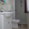 Bagno moderno con doccia, lavandino e servizi igienici su pavimento in legno chiaro.