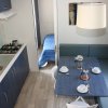 Interno di un bungalow con cucina e sala da pranzo, tavolo apparecchiato e divano blu.