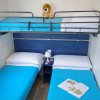 Camera con letti singoli e letto a castello, copriletto azzurri e un peluche sul letto superiore.
