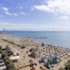 Spiaggia con ombrelloni e giochi per bambini, mare calmo sullo sfondo.