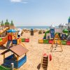 Parco giochi sulla spiaggia con numerosi scivoli colorati e strutture a tema castelli.