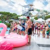 Persone in piscina con un gonfiabile a forma di fenicottero rosa.