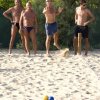 Quattro uomini giocano a bocce su una spiaggia sabbiosa.