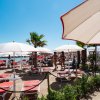 Spiaggia con lettini rossi e ombrelloni bianchi.