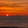 Tramonto sul mare con il sole parzialmente visibile all'orizzonte.