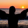 Silhouette di una persona che guarda un tramonto sul mare.