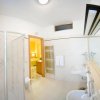Bagno moderno con doccia, specchio lungo e arredi bianchi.