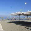 Una spiaggia con lettini e ombrelloni gialli sotto un cielo blu.