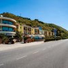 Edificio hotel giallo con balconi curvi, situato lungo una strada con sfondo montuoso.