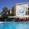 Piscina con persone, edificio con murale di un pesce blu su sfondo bianco.