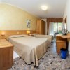 Camera d'albergo con due letti singoli, pavimento in marmo e mobili in legno chiaro.