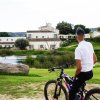 Uomo in bicicletta guarda un resort vicino a un laghetto.