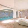 Stanza spa con piscina e lettini bianchi.