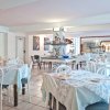 Sala da pranzo con tavoli apparecchiati, sedie bianche e decorazioni artistiche.