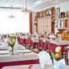 Sala da pranzo luminosa con tavoli apparecchiati e decorazioni floreali.