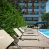 Lettini prendisole beige affiancano una piscina vicino a un edificio.