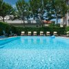 Piscina all'aperto circondata da lettini e alberi.