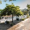 Un sentiero pedonale in legno accanto a un ristorante con tavoli all'aperto e alberi ombreggianti.