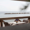 Tavolo per due sul mare con fiori al centro e barriera rocciosa sullo sfondo.