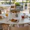 Tavolo all’aperto con colazione composta da succhi, dolci e frutta.