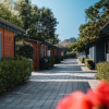 Un viale di bungalow colorati con finestre blu, contornato da siepi e alberi verdi.