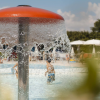 Una fontana a forma di fungo in una piscina con bambini che giocano attorno.