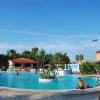 Piscina all'aperto con persone e chiosco, cielo sereno.