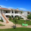 Complessi residenziali bianchi con scale esterne e vialetti in un giardino verde.