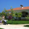 Famiglia passeggia in giardino davanti a una casa con tetto rosso.